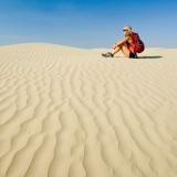 Eine junge Frau sitzt in den weiten Sandflächen der Great Sand Hills im Südwesten Saskatchewans