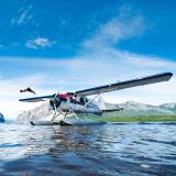 Ein Mann springt von einem Wasserflugzeug in einen See des Nahanni National Parks.