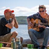 Zwei Männer spielen Musik am Ufer eines Sees