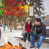 Ein junges Paar sitzt im winterlichen Saskatoon am Lagerfeuer.