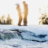 Ein Paar steht im Sonnenlicht an den verschneiten Pine Point Rapids im Whiteshell Provincial Park