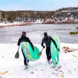 Surfer gehen durch den Schnee zum Wasser
